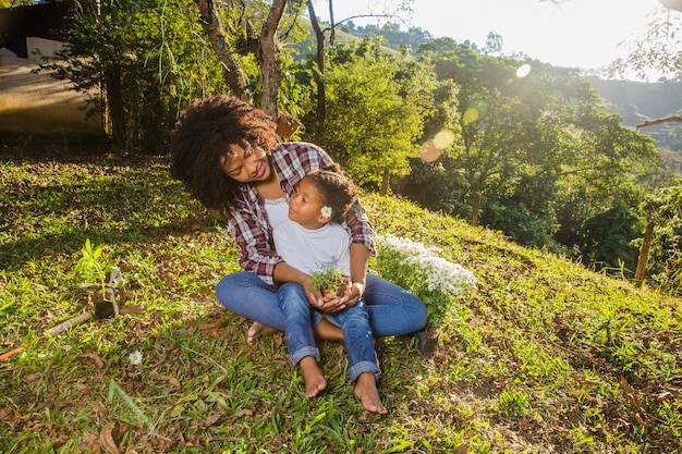 Junge Mutter mit Tochter sitzt auf einem Hügel