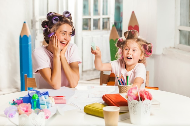 junge Mutter und ihre kleine Tochter zeichnen zu Hause mit Bleistiften