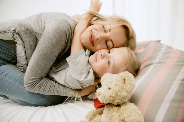 Kostenloses Foto junge mutter und ihre kleine tochter zu hause am sonnigen morgen. weiche pastellfarben. glückliche familienzeit am wochenende.