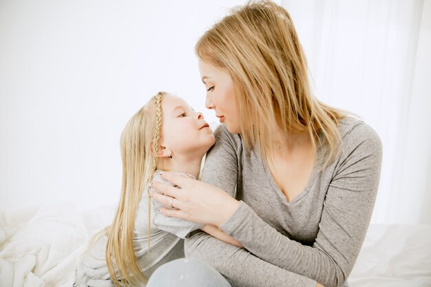 Junge Mutter und ihre kleine Tochter zu Hause am sonnigen Morgen