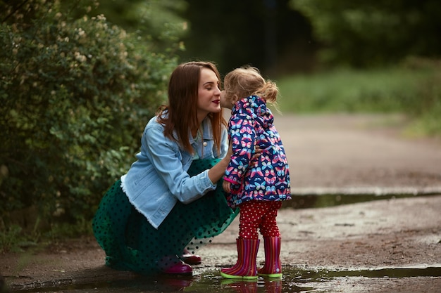 Junge Mutter und kleine Tochter haben den Spaß, der in gumboots auf den Pools im Park geht