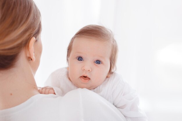 Junge Mutter und neugeborenes Baby im weißen Schlafzimmer