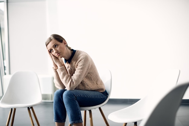 Junge nachdenkliche Frau, die auf den Beginn einer Gruppentherapie wartet