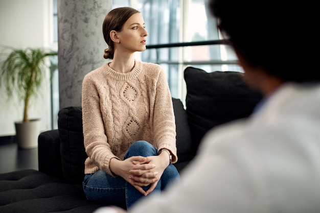 Kostenloses Foto junge nachdenkliche frau während eines psychotherapietermins in der arztpraxis