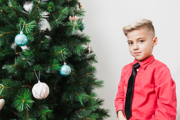 Junge neben Weihnachtsbaum