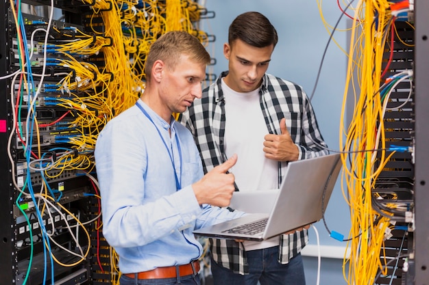 Junge Netzingenieure mit einem mittleren Schuß des Laptops