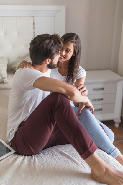 Junge Paare auf dem Bett, das einander betrachtet