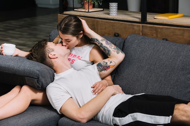 Kostenloses Foto junge paare, die auf couch küssen