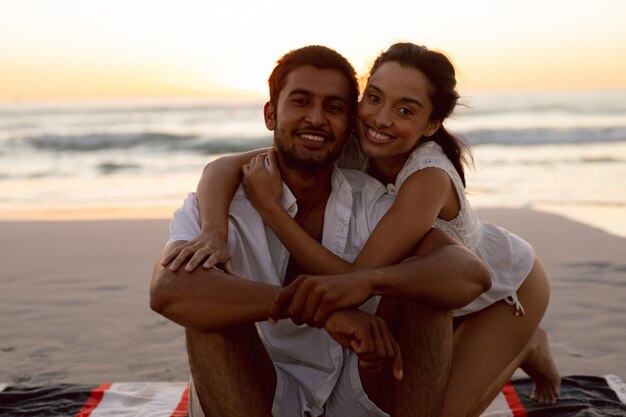 Junge Paare, die auf dem Strand sich umfassen
