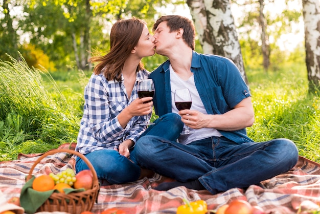 Junge Paare, die auf Picknick küssen