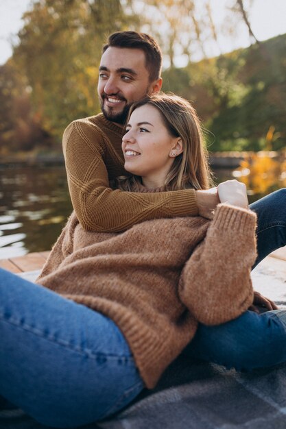 Junge Paare, die auf Plattformbrücke durch den Fluss sitzen