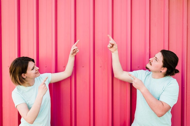 Junge paare, die aufwärts ihren finger gegen wellblech zeigen