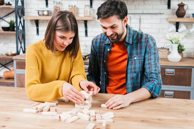 Junge Paare, die den Holzklotz auf Tabelle in der Küche stapeln