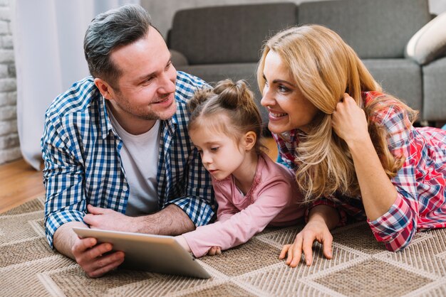 Junge Paare, die einander während Tochter verwenden digitale Tablette betrachten