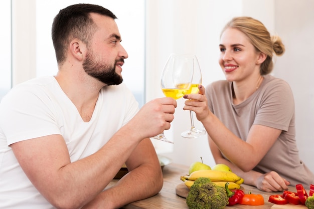 Junge Paare, die Gemüse essen und zusammen trinken