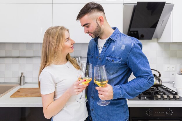 Junge Paare, die Gläser Wein in der Küche klopfen
