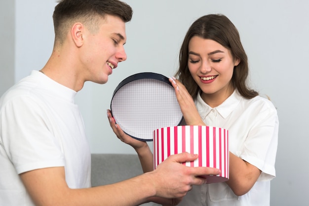 Junge Paare, die große Geschenkbox auf Couch öffnen