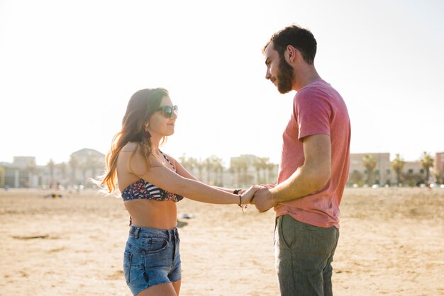 Junge Paare, die Hand des anderen stehen, die auf Strand steht