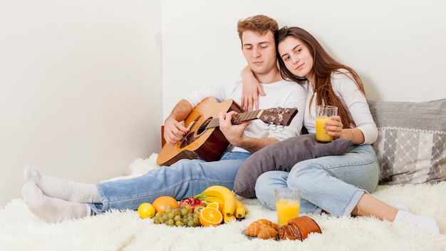 Junge Paare, die im Bett frühstücken