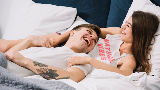 Junge Paare, die im Bett lachen
