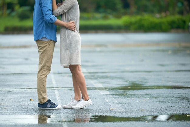 Junge Paare, die im Regen küssen