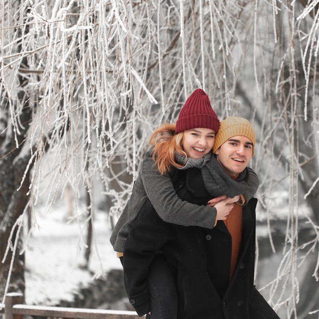 Junge Paare, die in der Winterlandschaft sich halten