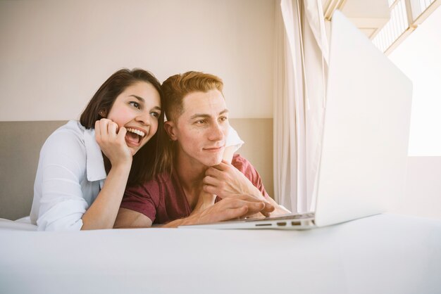 Junge Paare, die Laptop auf Bett betrachten