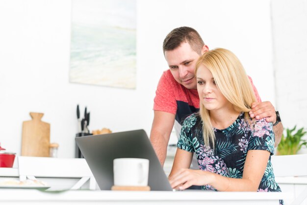 Junge Paare, die Laptopschirm betrachten