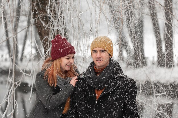 Junge Paare, die mit dem Schnee lächeln und spielen