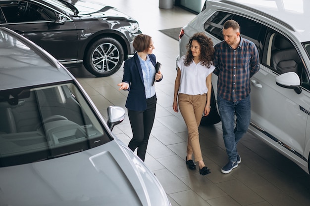 Junge Paare, die mit einem Verkäufer in einem Autosalon sprechen