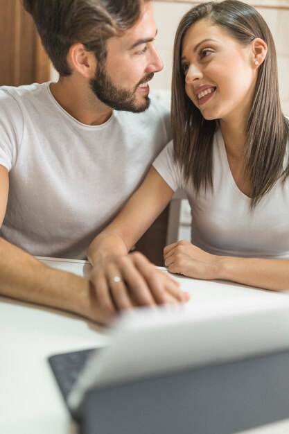 Junge Paare, die nahe Tablette sich betrachten