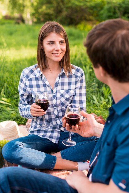 Junge Paare, die Picknick haben und Weingläser halten
