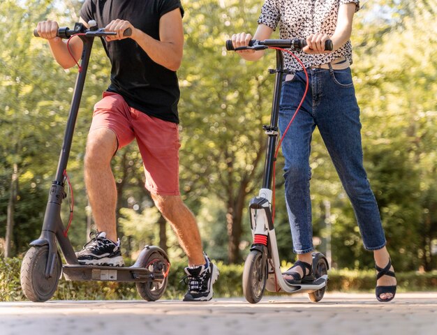 Junge Paare, die Roller draußen reiten