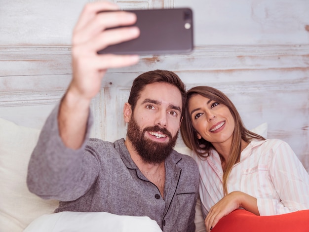 Junge Paare, die selfie im Bett nehmen