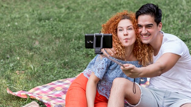 Junge Paare, die selfies nehmen und Spaß während eines Picknicks haben
