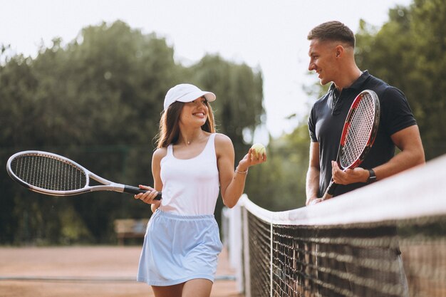 Junge Paare, die Tennis am Gericht spielen