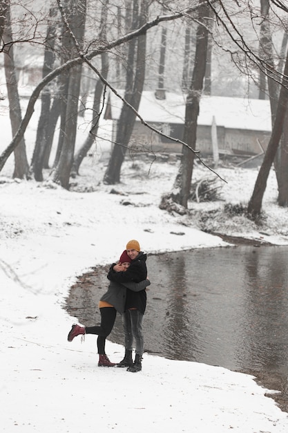 Kostenloses Foto junge paare in der winterlandschaft mit bäumen und see