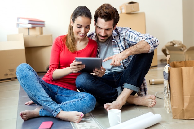 Junge Paare mit digitaler Tablette in ihrem neuen Haus