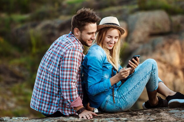 Junge Paare von Reisenden lächelnd, Telefon betrachtend