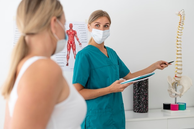 Junge Physiotherapeutin hilft einem Patienten mit Rückenproblemen