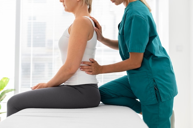 Junge Physiotherapeutin hilft einem Patienten mit Rückenproblemen
