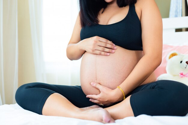 Junge prenant Frau, die ihren Bauch mit Liebe berührt