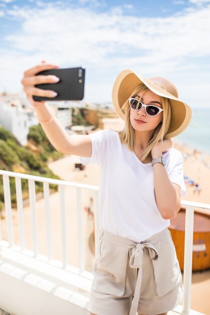 Junge reisende Frau, die Telefon hält Selfie gegen Meer macht