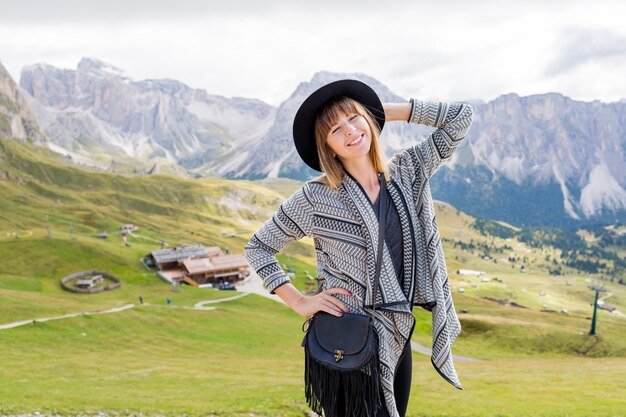 Junge reisende Frau mit Hut und Rucksack, die erstaunlichen Bergblick genießen
