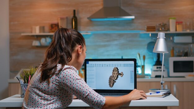 Junge Remote-Architektin, die an modernen CAD-Programmüberstunden arbeitet. Industrielle Ingenieurin, die Prototypidee auf PC studiert und CAD-Software auf dem Gerätedisplay zeigt