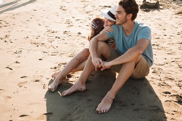 Junge romantische Paar sitzt auf dem Sand