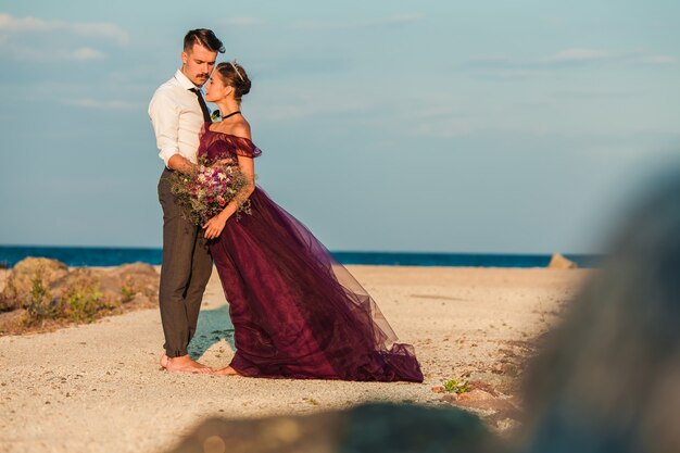 Junge romantische Paare, die auf dem Strand aufpasst den Sonnenuntergang sich entspannen