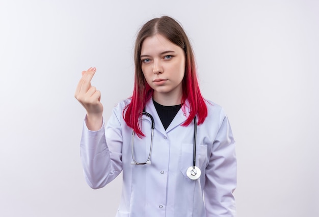 junge Ärztin, die medizinisches Gewand des Stethoskops trägt, das Spitzengeste auf isolierter weißer Wand zeigt