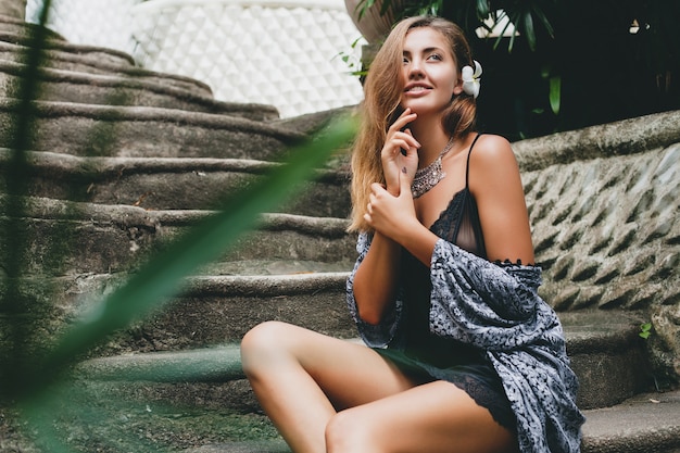 Junge schlanke Frau in tropischer Bali-Villa, die sexy Dessous, sinnliche, schöne, flirty, gebräunte Haut, trendige Kleidung, ethnischen Boho-Stil, Nachthemd, Umhang, natürliche Schönheit trägt