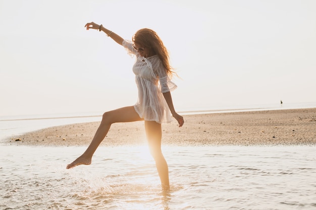 Junge schlanke schöne Frau am Sonnenuntergangsstrand